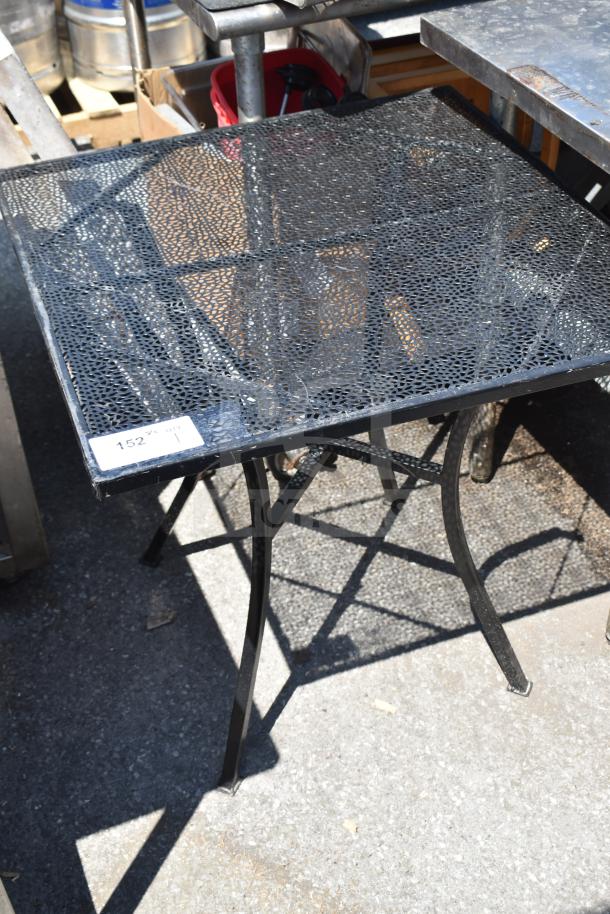 Black mesh patio table with square top and curved legs, in fair condition, auction tag “152” visible on corner.
