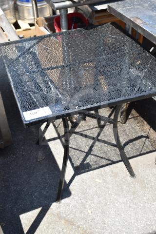 Black mesh patio table with square top and curved legs, in fair condition, auction tag “152” visible on corner.
