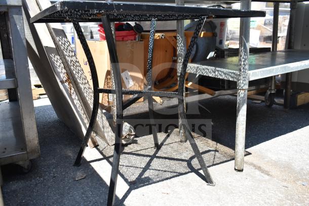 Black mesh patio table with curved legs, showing a decorative pattern. Good condition, suitable for outdoor use.