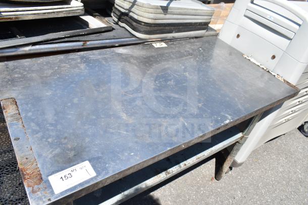 Commercial steel table with under shelf, moderate wear, minor rust on edges, label showing auction lot number 153.