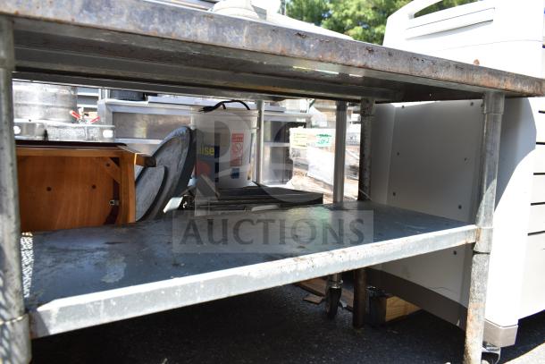 Commercial table with under shelf, metal construction, industrial use, visible rust spots, sturdy design.