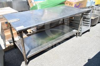 Commercial stainless steel table with under shelf, showing moderate wear. Includes label marking "169". Suitable for heavy-duty use.