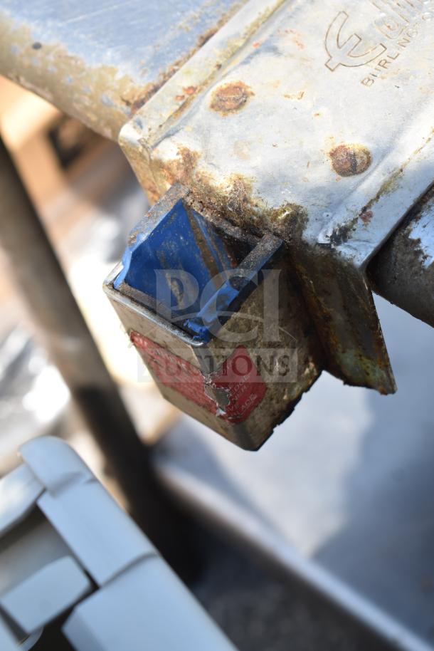 Rusted metal section of a commercial table with visible label; features durable construction and under shelf for storage.