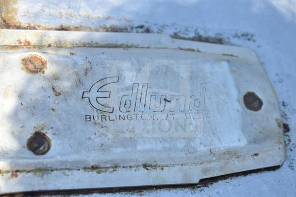 "Edlund commercial table tag, Burlington, VT, USA, shows visible rust and wear on metal surface; useful for vintage or industrial setups."