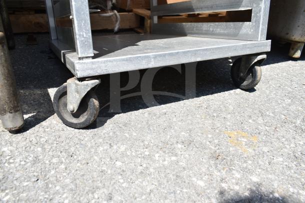 Commercial pan transport rack on sturdy commercial casters, in good condition, showing metal frame and rolling wheels.