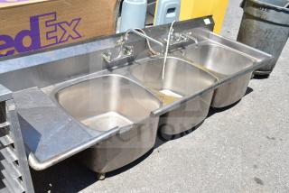 Commercial 3 bay stainless steel sink, no legs, used condition. Features three compartments and dual faucets.