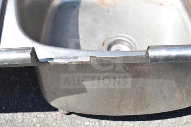 Commercial 3 bay stainless steel sink, no legs, visible wear and rust, ideal for kitchen use, durable construction.