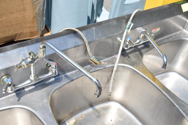 Commercial 3 bay sink without legs, stainless steel, visible faucet connections, used condition, no visible brand markings.