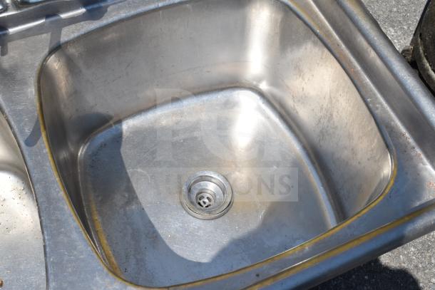 Stainless steel commercial 3 bay sink without legs, sturdy design, minor wear, ideal for restaurant use.