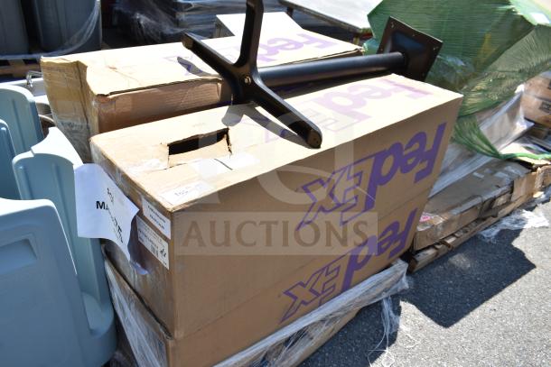 Boxes labeled "FedEx" containing new scratch and dent outdoor table bases on a pallet. Tags and labels present.