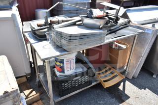 Commercial table with under shelf containing bus bin lids, chair, metal bowl, and a container. Good condition with visible wear.