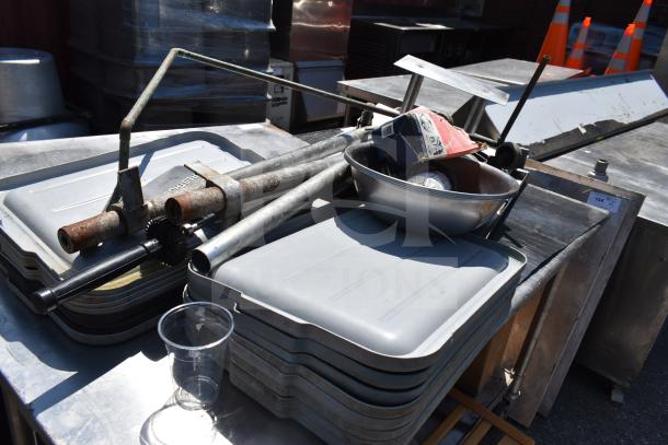 Commercial table with under shelf and contents, including stacked bus bin lids, a metal bowl, and miscellaneous items. Used condition.