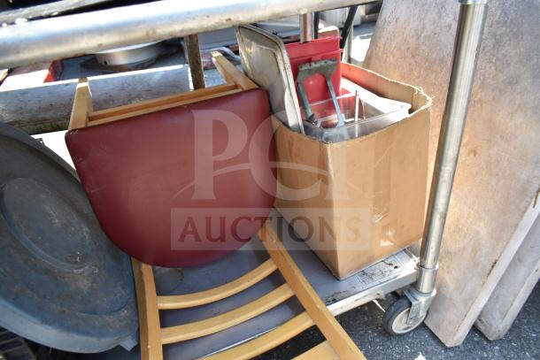 Commercial table with under shelf, holding bus bin lids, a chair, and a bowl. Includes a cardboard box with contents.