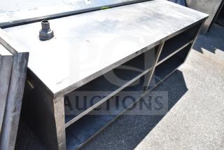 Commercial table with under shelves, stainless steel, used condition, features multiple storage shelves, durable build.