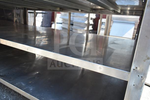 Commercial table with under shelves, stainless steel, used condition, sturdy construction, suitable for industrial use.