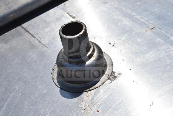 Commercial table with metal surface; minor wear visible. Features under shelves for storage, designed for industrial use.