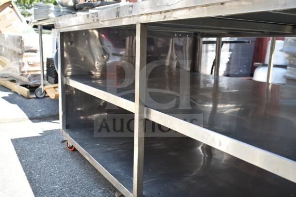 Commercial table with under shelves, stainless steel, good condition, on wheels for mobility, ideal for kitchen use.