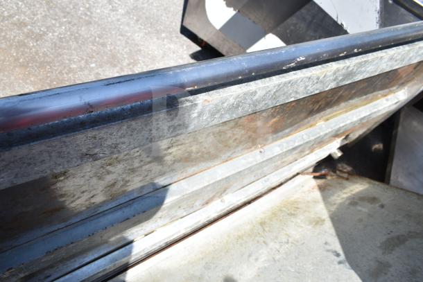 Corroded metal tabletop with visible rust and scratches, signifying heavy use and wear. No labels or markings visible.