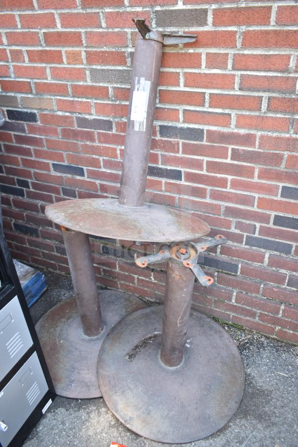 Set of three metal table bases with round supports and mounting hardware. Visible wear and rust, suitable for restoration.