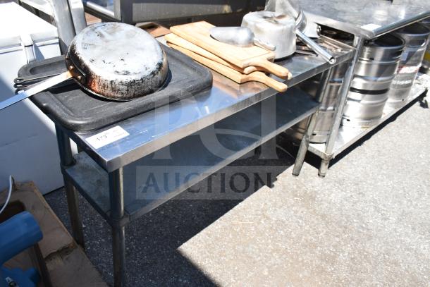 Commercial stainless steel table with under shelf, includes cutting boards, cookware, and utensils; used condition.