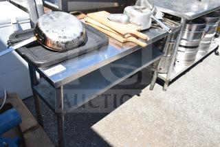 Commercial stainless steel table with under shelf, includes cutting boards, cookware, and utensils; used condition.