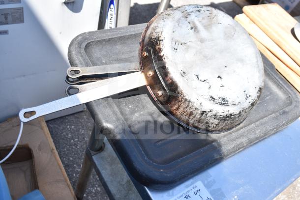 Commercial table with under shelf holding worn frying pans and cutting boards, good condition, auction label visible.
