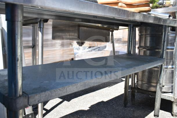 Commercial table with under shelf, stainless steel, used condition, includes contents like cutting boards.