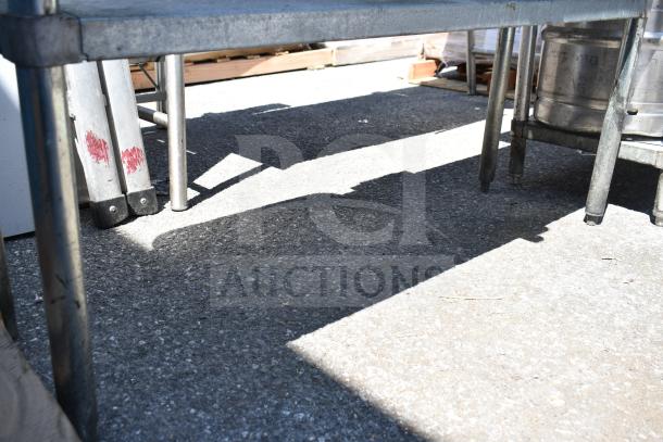 Commercial table with under shelf, sturdy metal frame, minor surface wear, includes attached contents beneath shelf.