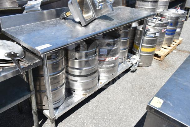 Commercial stainless steel table with under shelf holding multiple metal kegs. No sink included. Slight wear visible.