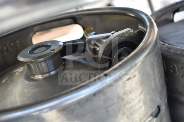 Commercial table with under shelf, includes metal kegs. Excludes sink. Features visible wear, sturdy construction.