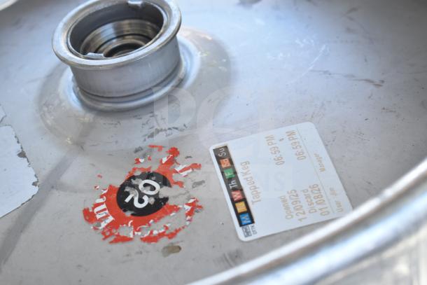 Commercial table with under shelf, containing kegs. Visible keg label details: "Tapped Keg," opened on 12/09/25, discard by 01/08/26.