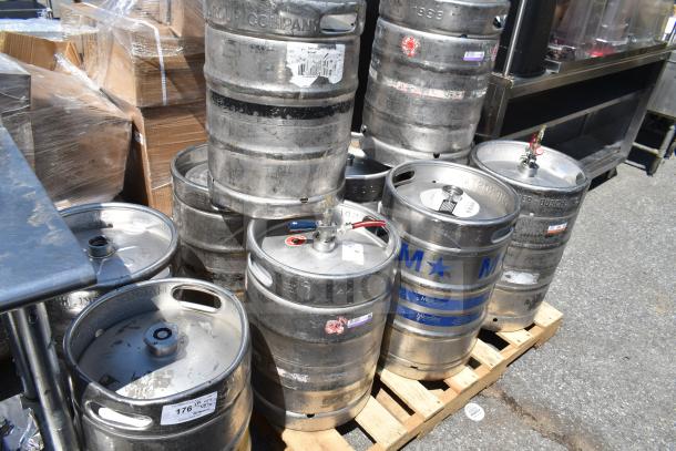 Ten half-size barrel kegs on a pallet, used condition, visible labels with assorted brand markings.