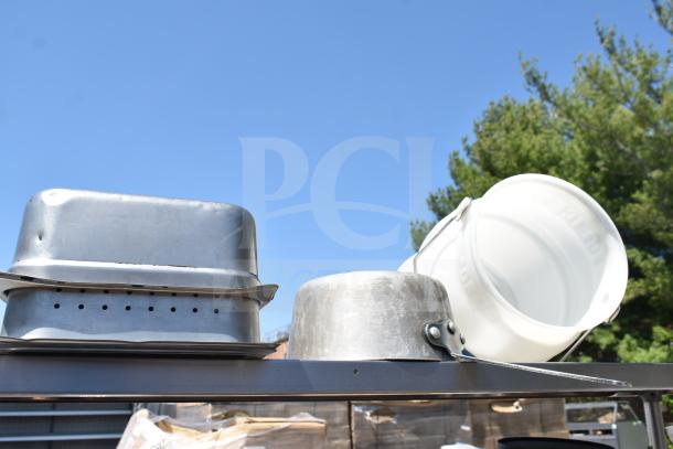 Commercial table with two-tier over shelf and under shelf, containing metal pans and a white bucket, in good condition.