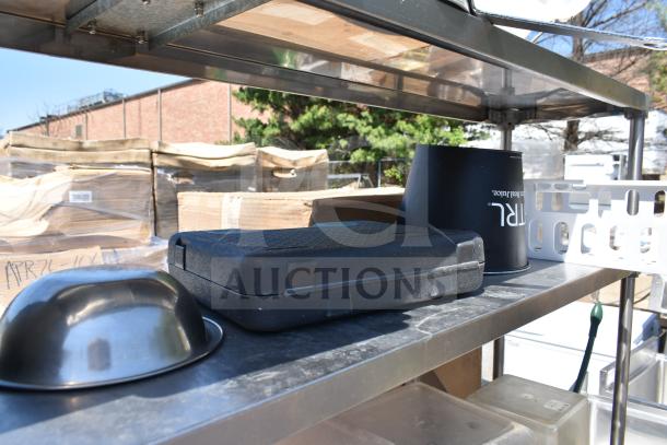 Commercial table with 2-tier overshelf and undershelf, includes black case, metal bowl, and assorted contents, used condition.