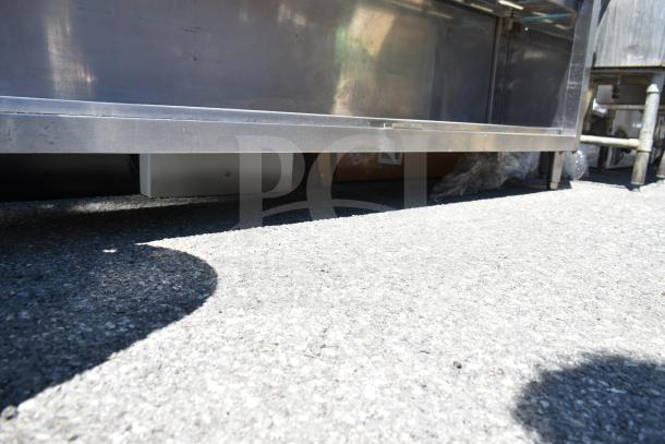 Commercial stainless steel table with two-tier over shelf and under shelf, includes boxed contents and packaging below.