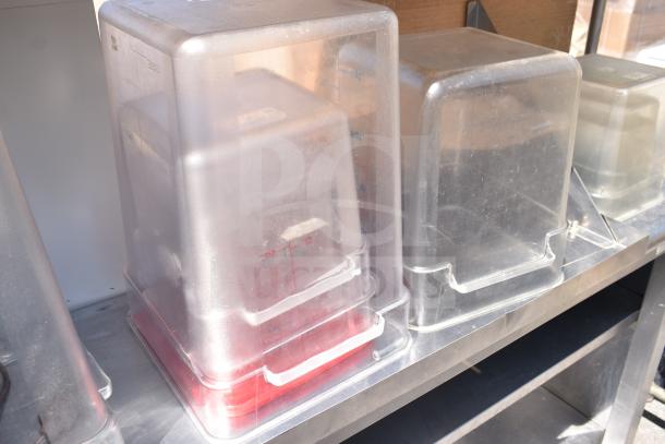 Commercial table with two-tier over-shelf and under-shelf, contains multiple covered storage containers, stainless steel.