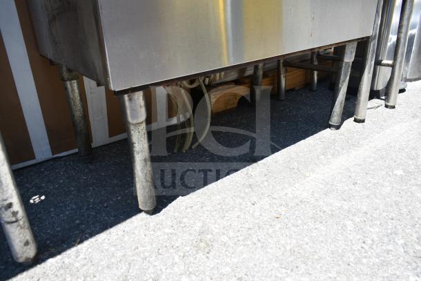 Commercial stainless steel ice bin with cold plate and multiple connected hoses, on sturdy metal legs, good condition.