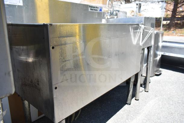 Commercial ice bin with cold plate, stainless steel, sturdy legs, visible wear marks, suitable for heavy-duty use.