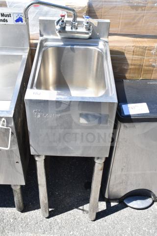 Commercial single bay sink with dual faucet, stainless steel, embossed with "L&JNY," showing light wear, on sturdy legs.