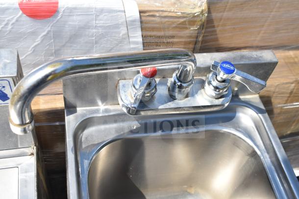 Commercial single bay stainless steel sink with dual lever faucets, chrome finish, and slight wear visible.
