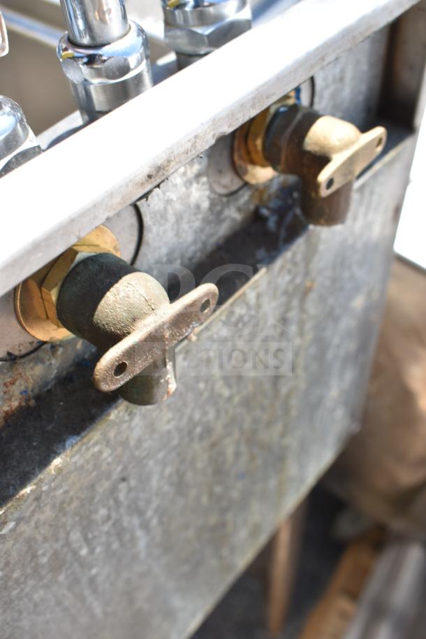 Commercial single bay sink with stainless steel valves, rustic finish, visible wear; features durable construction for heavy use.