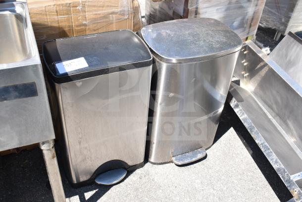 Two metal foot pedal trash cans, stainless steel, square design, moderate wear, one with a visible label.