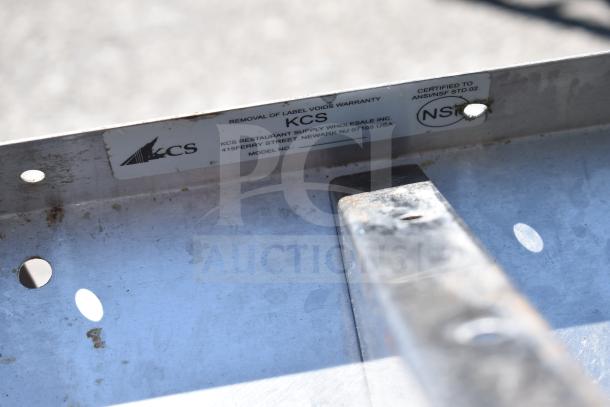 KCS stainless steel wall mount shelf, ANSI/NSF certified, visible label with warranty details, slightly worn condition.