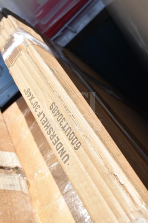 Brown cardboard box labeled "UNDERSHELF 30x48, 6000U30485." Box shows minor wear. Contains new, scratch and dent items.