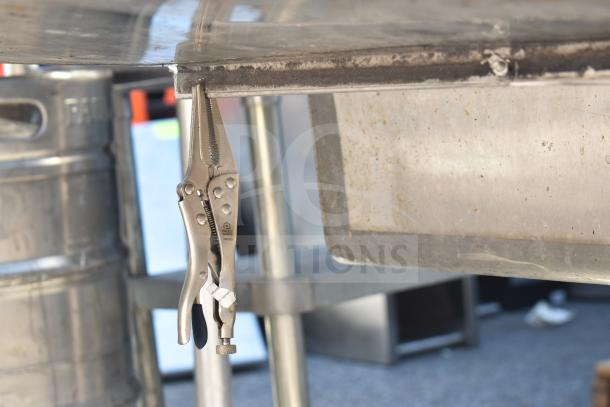 Stainless steel dish table with pliers attached, showing clean and dirty sections. Functional, industrial-grade condition.
