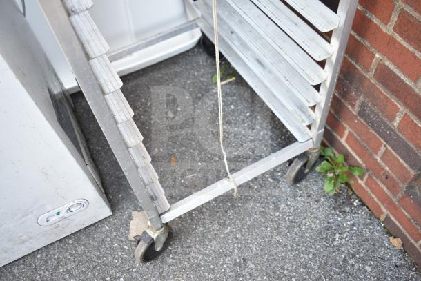 Commercial pan transport rack with multiple shelves on sturdy commercial casters, used condition.