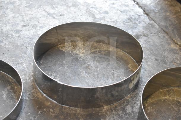 Twelve stainless steel round collars, new condition, displayed on a concrete surface. Auction lot multiplies bid by 12.