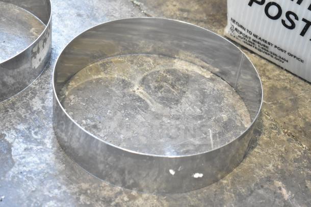 Stainless steel round collars in used condition on metal surface, part of a 12-item auction lot.