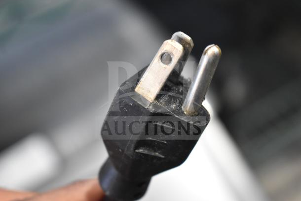 A close-up of a power plug for the 2016 Hobart HTi-7LH commercial scale, showing the prongs and the black plastic casing.