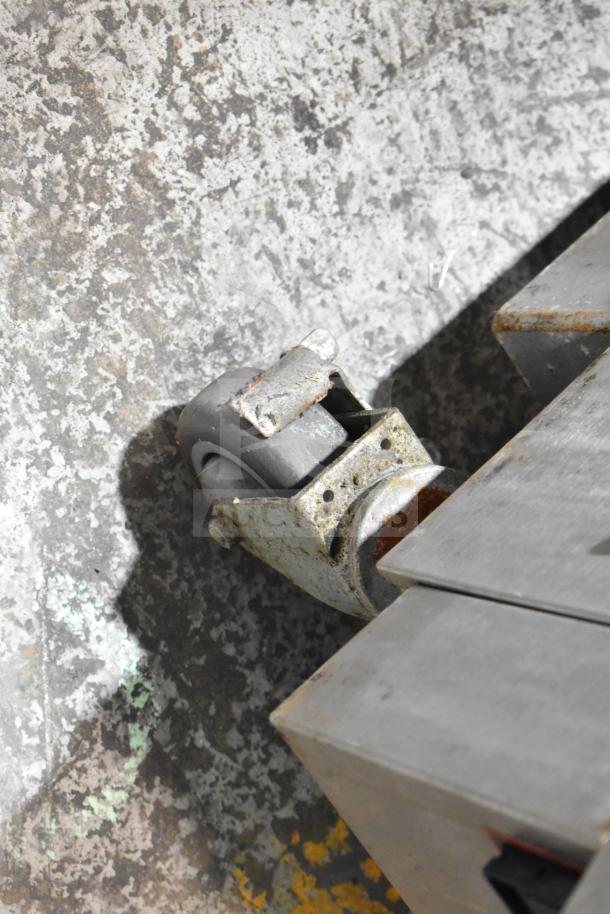 2019 Garland CXPB12 electric clamshell griddle caster wheel detail, showing wear and mounting hardware.